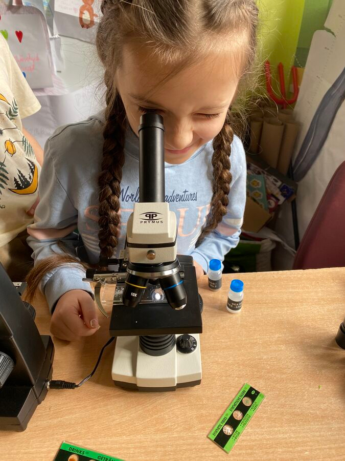 Dziewczynka patrzy przez mikroskop.