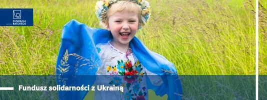 Fundusz Solidarnośc z Ukrainą.  W tle uśmiechnięte dziecko w wianku z flagą Ukrainy na plecach.